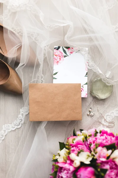 Davetiyeler düğün kağıtları masaya döşeme çiçekler, vual, yüksek topuklu ayakkabılar ve bir şişe tuvalet suyu ile süsleyin. Mockup boş kartpostal ile 