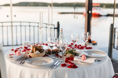 Romantik Sevgililer günü akşam yemeği ayarda gül yaprakları ve boş kadehlerin günbatımı