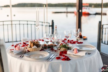 Romantik Sevgililer günü akşam yemeği ayarda gül yaprakları ve boş kadehlerin günbatımı