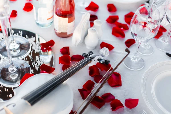 Romantik Sevgililer günü akşam yemeği şampanya, gül, gül yaprakları ve keman