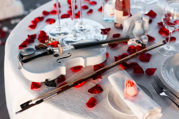 Romantik Sevgililer günü akşam yemeği şampanya, gül, gül yaprakları ve keman