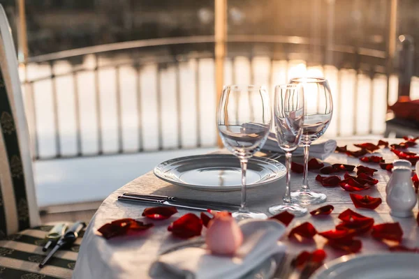 Romantik Sevgililer günü akşam yemeği ayarda gül yaprakları ve boş kadehlerin günbatımı