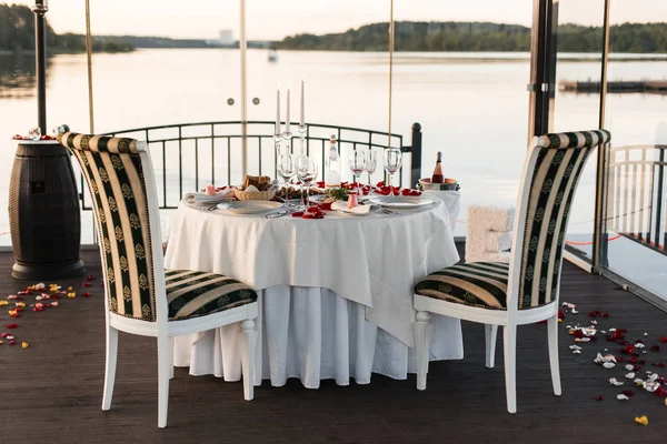 Romantik Sevgililer günü akşam yemeği ayarda gül yaprakları ve boş kadehlerin günbatımı