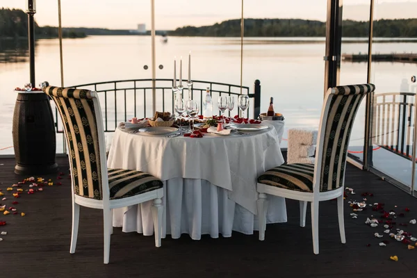 Romantik Sevgililer günü akşam yemeği ayarda gül yaprakları ve boş kadehlerin günbatımı