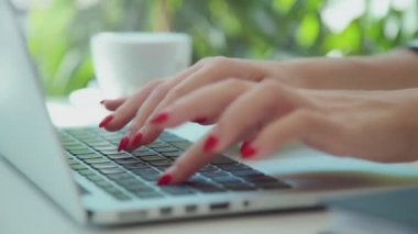 Genç eller temiz kırmızı manikür laptop klavye üzerinde baskı ile