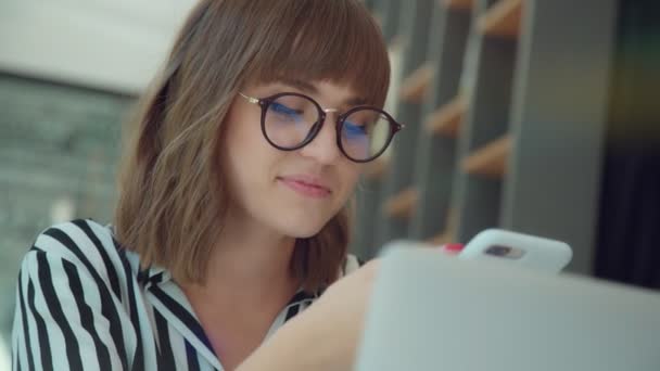 Jeune fille élégante dans une chemise rayée et des lunettes avec un téléphone — Video