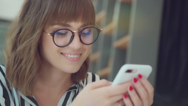 Een jonge, succesvolle vrouw kijkt naar de telefoon en de glimlach. — Stockvideo