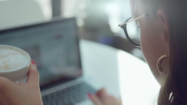 Tas från baksidan. Laptop och kaffe kopp i ramen. — Stockvideo