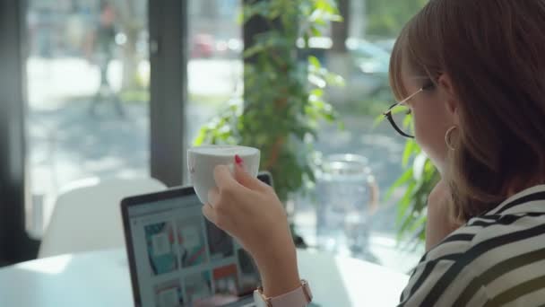 Mujer elegante con un ordenador portátil está bebiendo café, mujer de negocios joven . — Vídeos de Stock