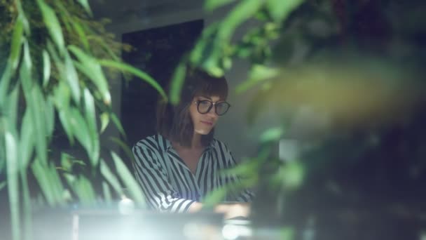 Elegante joven sentada a la mesa en la cafetería sola y usando una computadora portátil — Vídeos de Stock