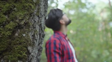 Bir adam dikkatle ve ilgiyle moss ile uzun bir ağaç olarak görüyor