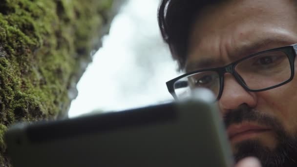 Ecologist studies moss on a tree and writes data to a tablet computer. — Stock Video