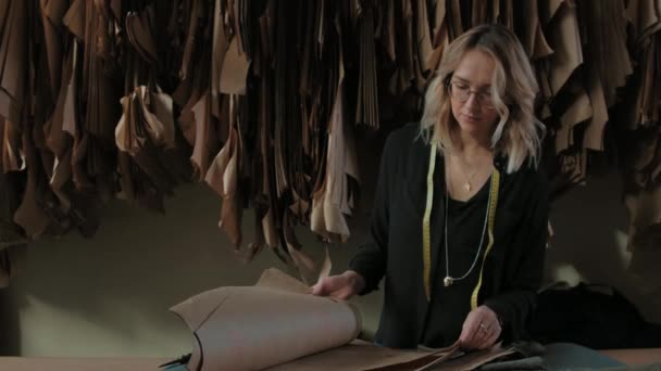 Seamstress works in a texture studio, examines drawings of clothes — Stock Video