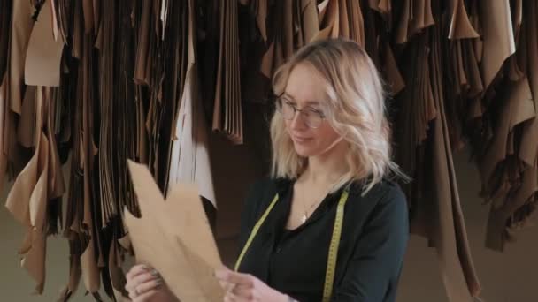 Loira costureira elegante examina o padrão de roupas futuras . — Vídeo de Stock