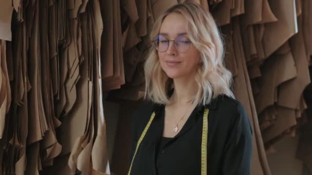 Eine junge blonde Frau in einem Nähstudio und studiert Schnittmuster — Stockvideo