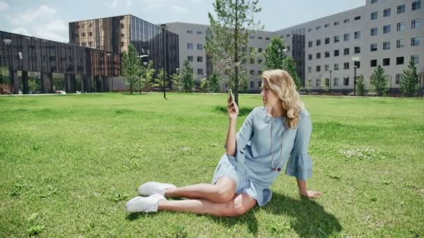スマート フォンで緑の草にブルー ジーンズ、ドレスの現代の若い女性 — ストック動画