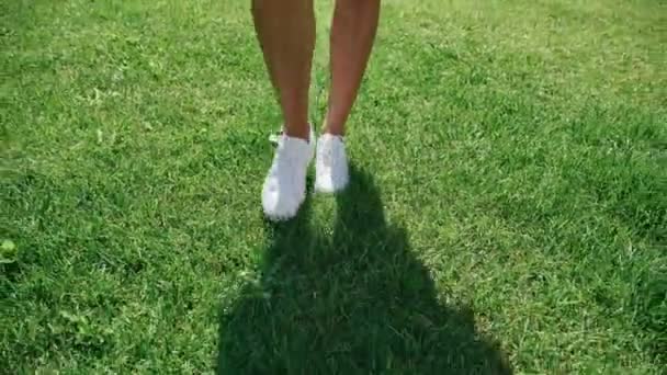 Walking on the lawn in white shoes: close-up, only legs and shadow — Stock Video