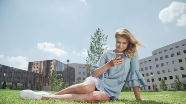 Mooie jonge vrouw buiten met een mobiele telefoon surfen op het Internet. — Stockvideo