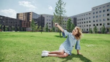 Smartphone ile yeşil çimenlerin üzerinde genç kadın resimleri, selfie alır.
