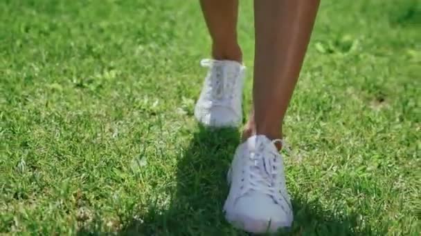 Slanke vrouwelijke benen in witte schoenen rechtdoor — Stockvideo