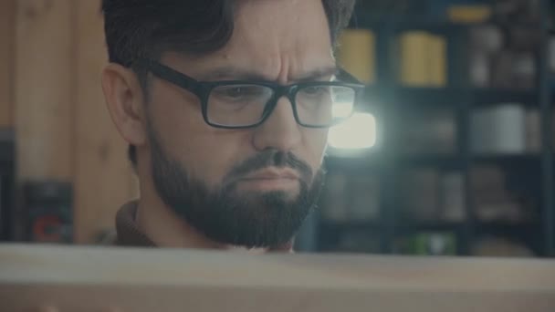 Carpenters face with beard, glasses: attentively checks the quality. — Stock Video