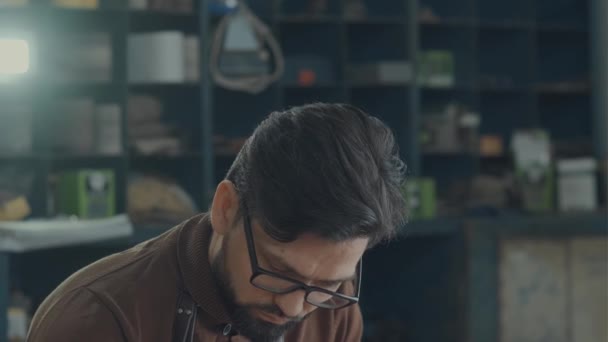 Portrait d'un brunettiste à lunettes, barbe et tablier de travail — Video