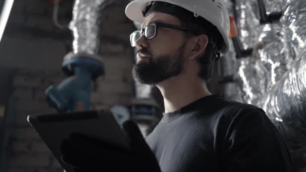 Инженер-техник в шлеме работает в котельной с планшетом — стоковое видео