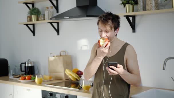 Manhã feliz: homem 30 tem um café da manhã saudável, usando smartphone — Vídeo de Stock