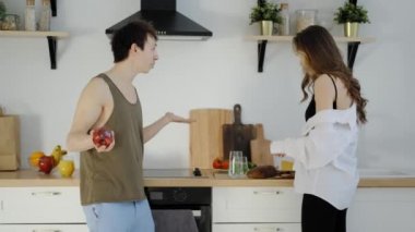 Genç evli çift güneşli mutfakta kahvaltı hazırlıyor..