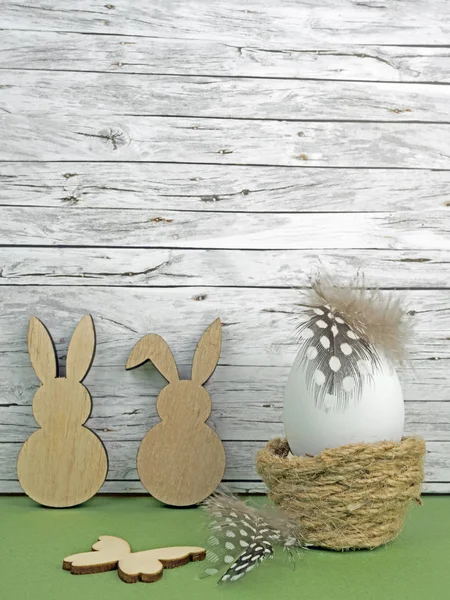 Easter background with Easter egg, Easter bunnies and butterfly isolated on green in front of wood
