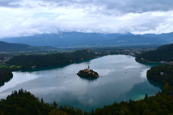 View of lake Bled and the island with the church on a cloudy day in Gorenjska, Slovenia