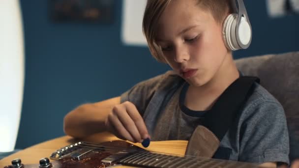 Jongen in hoofdtelefoons lied met gitaar leren — Stockvideo