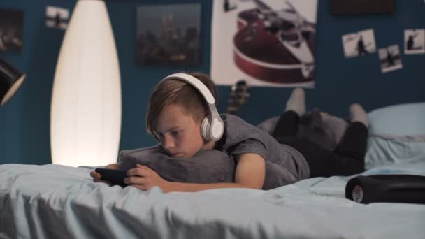 Jongen smartphone spelen op bed — Stockvideo