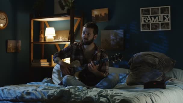 Pareja juguetona cantando con guitarra en la cama tarde en la noche — Vídeos de Stock