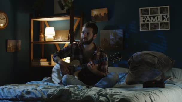 Pareja juguetona cantando con guitarra en la cama tarde en la noche — Vídeo de stock