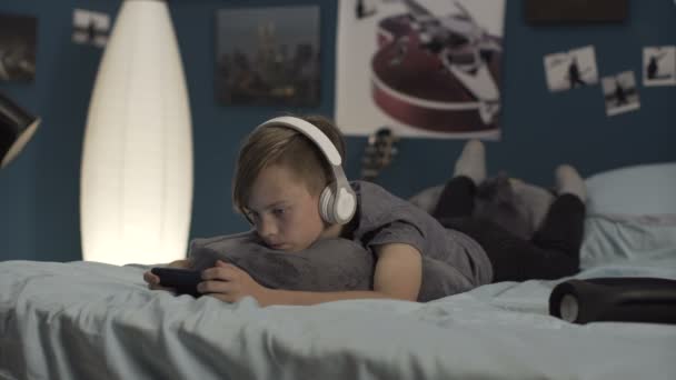Мальчик играет в смартфон на кровати — стоковое видео