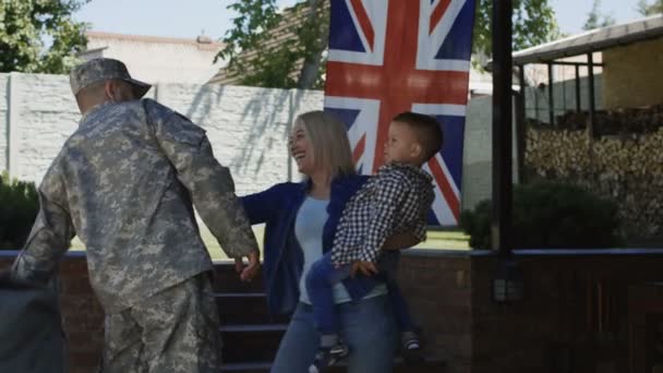 兴奋的妇女与儿童欢迎军人回到家里拥抱和笑对英国国旗愉快 — 图库视频影像