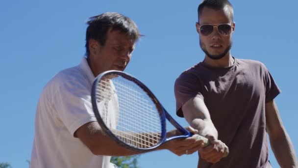 Tränare som visar badmintonracketens placering till mannen — Stockvideo