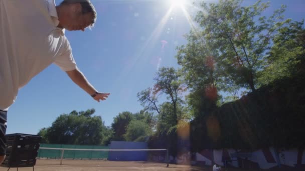 Člověk praktikující tenis slouží na slunci — Stock video