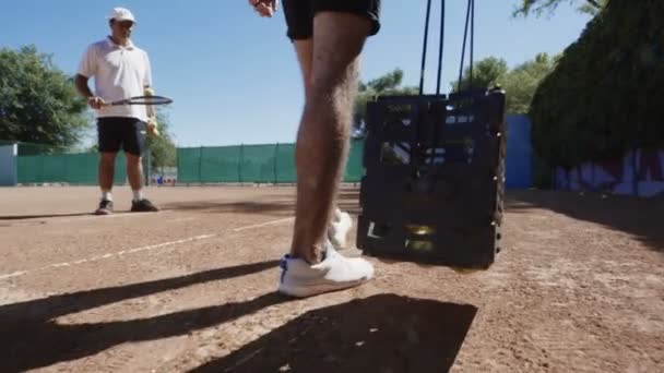 Hombre recogiendo pelotas de tenis en pista — Vídeos de Stock