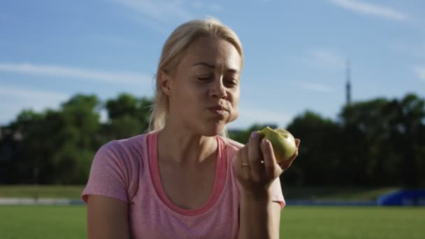 フィールドに太陽の下で女性の食用リンゴ — ストック動画