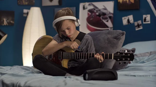 Pojke i hörlurar lärande låt med gitarr — Stockfoto