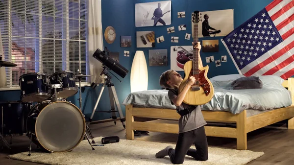 Etkileyici genç yatak odasında gitar çalmak