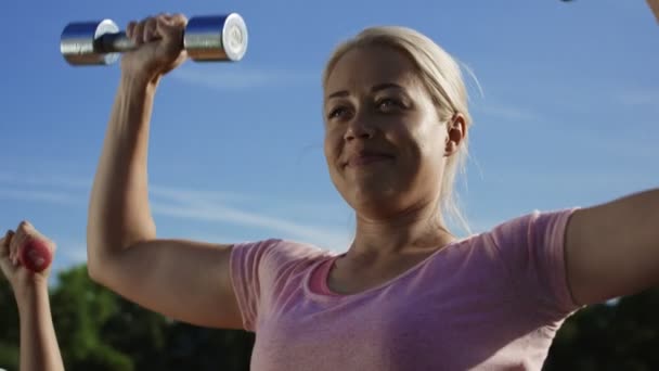 Mujer entrenando con pesas a la luz del sol — Vídeos de Stock