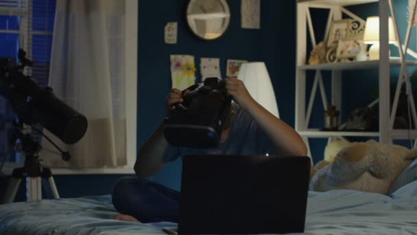 Menino usando óculos VR e laptop na cama — Vídeo de Stock