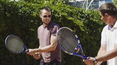 Trainer showing racket position to man clipart