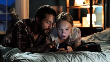 Genç çift sörf smartphone yatakta