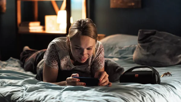 Jonge vrouw surfen smartphone op bed — Stockfoto