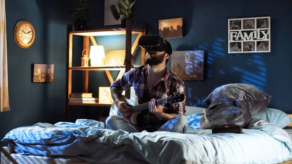 Hombre tocando la guitarra en gafas VR en la cama — Foto de Stock