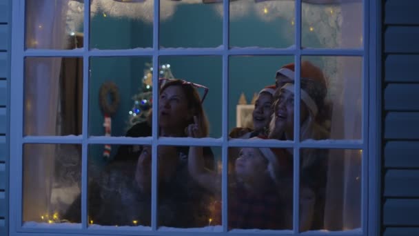 Familia feliz viendo fuegos artificiales a través de la ventana — Vídeo de stock